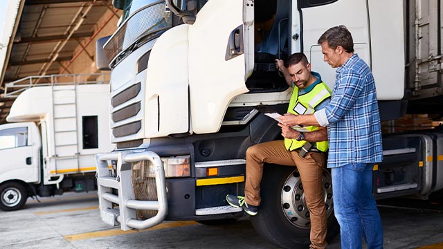 Supervisión de un camión en un centro logístico, representando la importancia de la gestión de flotillass para garantizar eficiencia operativa y cumplimiento de mantenimiento preventivo.