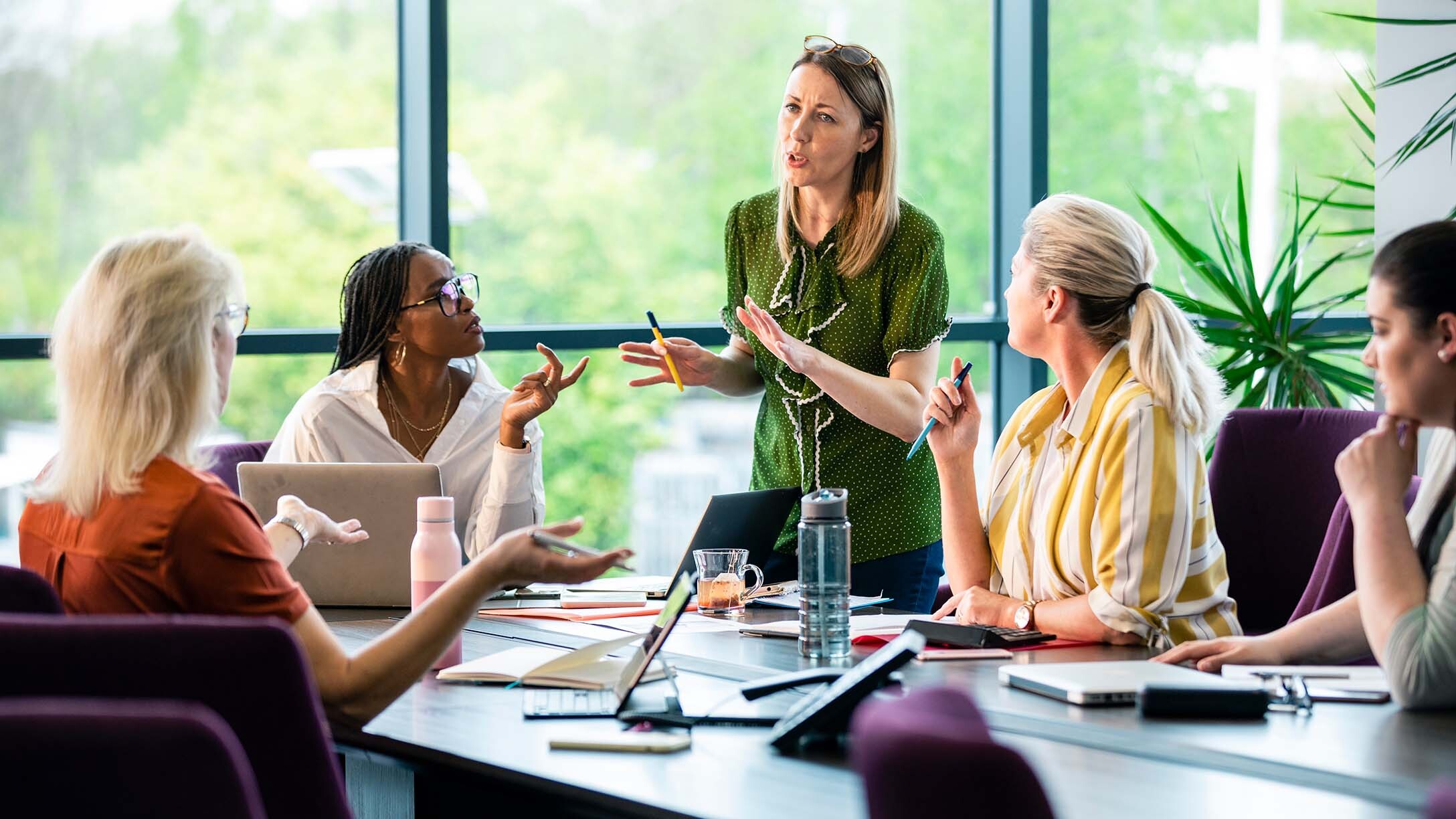 A woman explaining in front of other women employees in a meeting room.