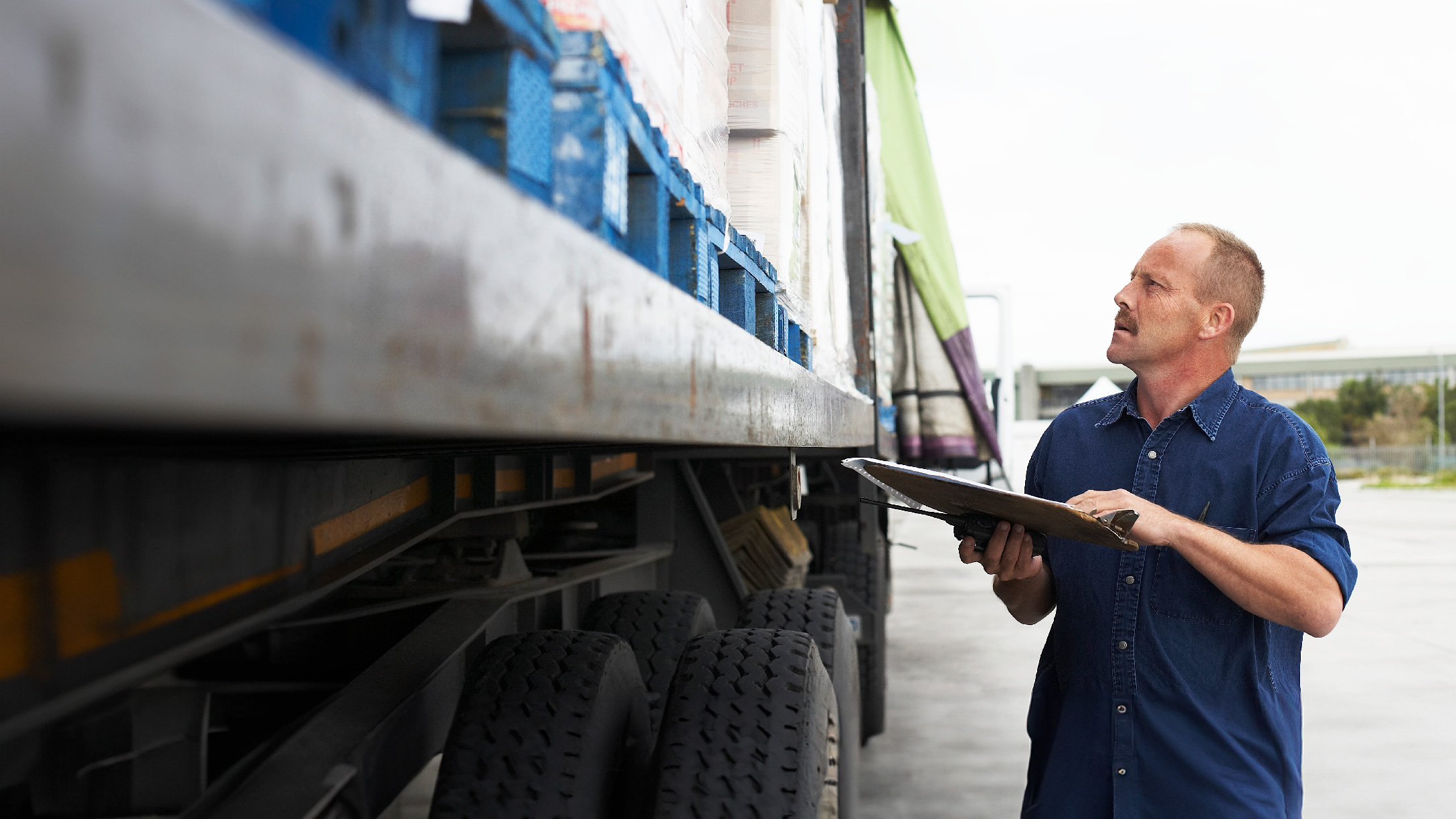 Person standing outside a truck doing holding a tablet