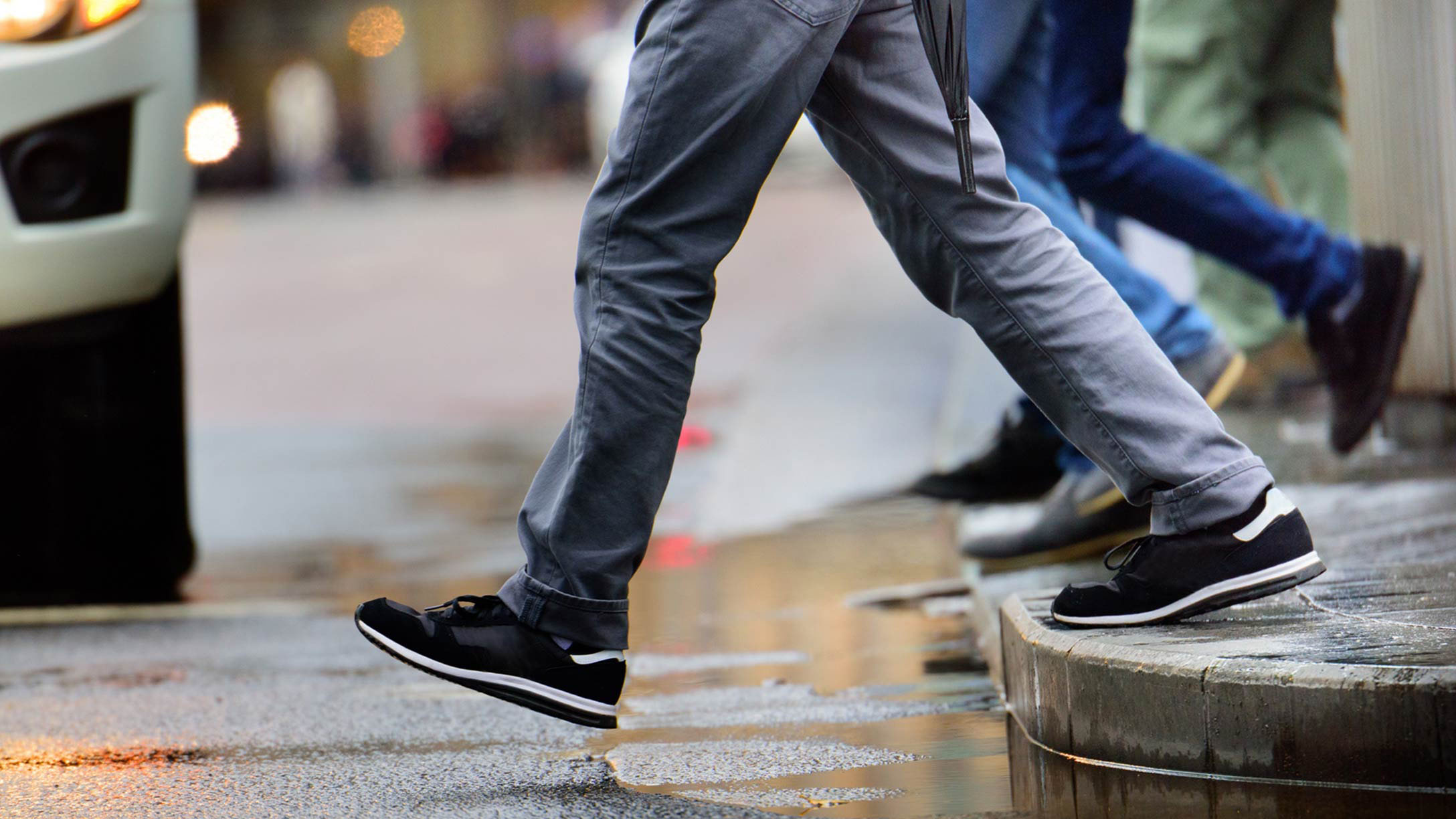 Two men crossing the road with a vehicle in front of them