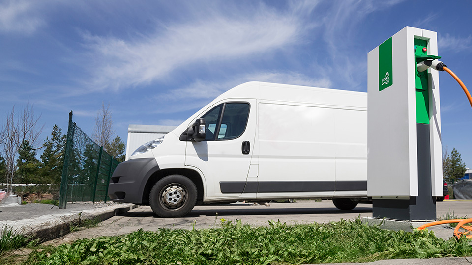 White electric van at a charging station 