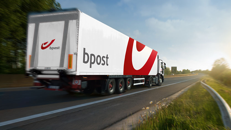 A bpost lorry is driving along a country road.