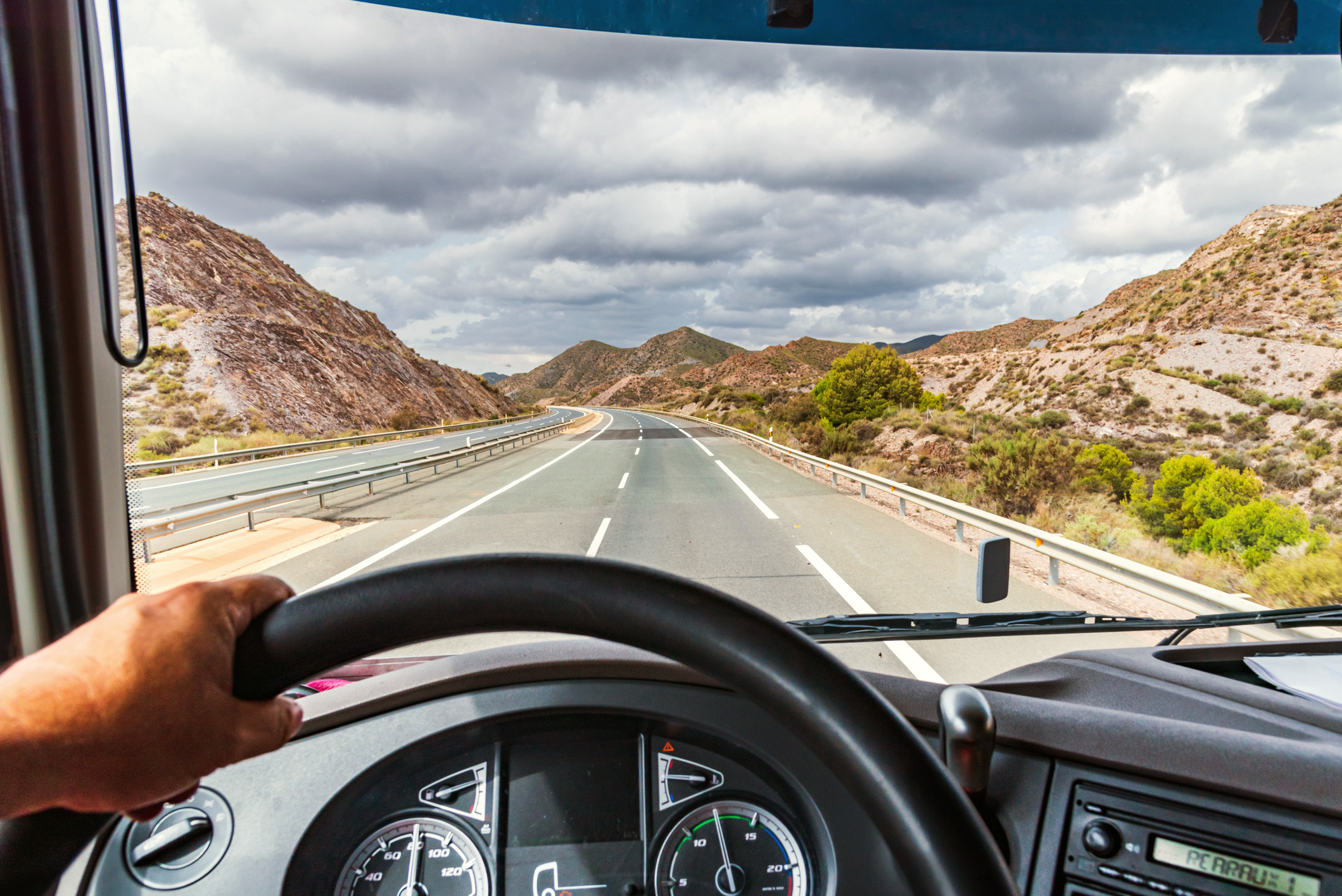Front view of the driver, driving a truck, looking into the road ahead. 