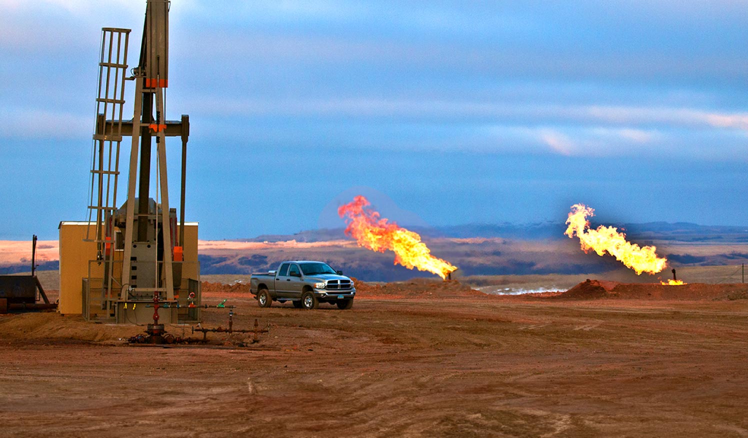 Plataforma de petróleo y gas con llamaradas y camioneta en sitio de perforación
