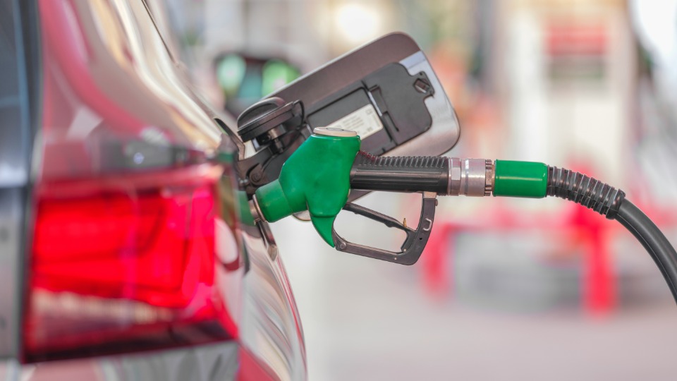 Pompa di rifornimento di colore verde in azione su una macchina ferma ad una stazione di servizio.