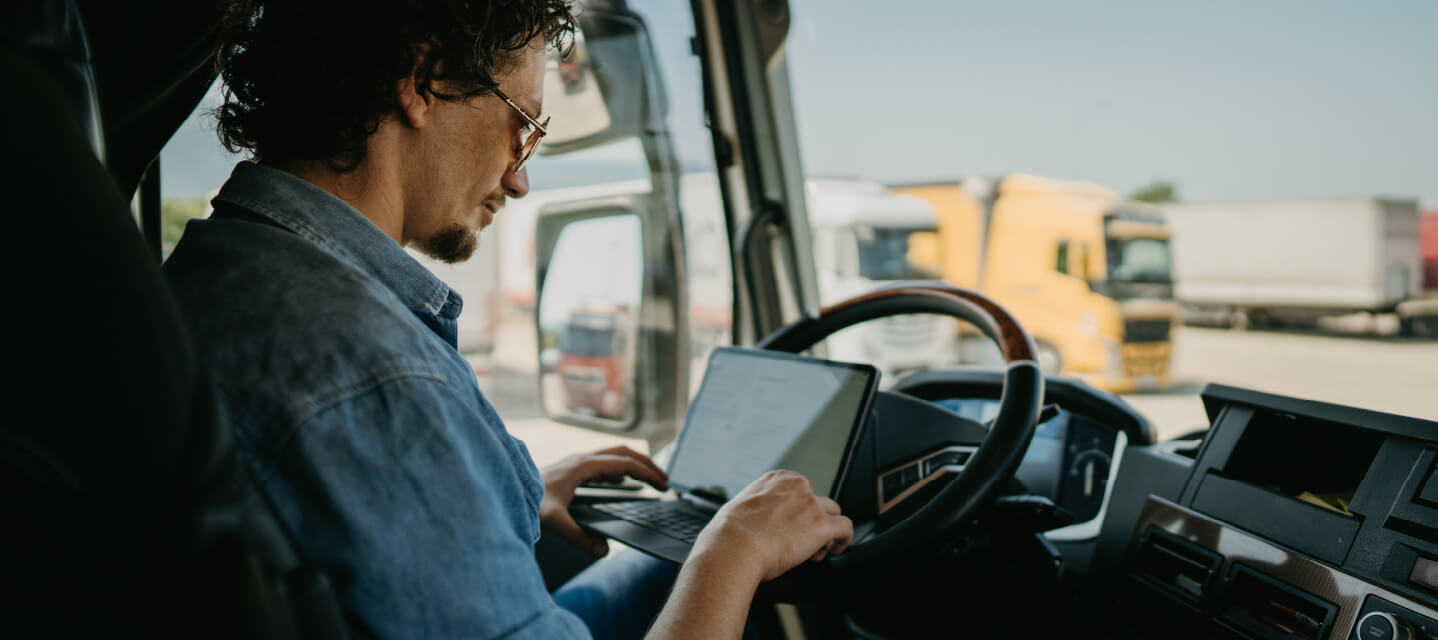 motorista dentro do caminhão verificando um tablet com dados do seu compartamento e a rota que precisa fazer