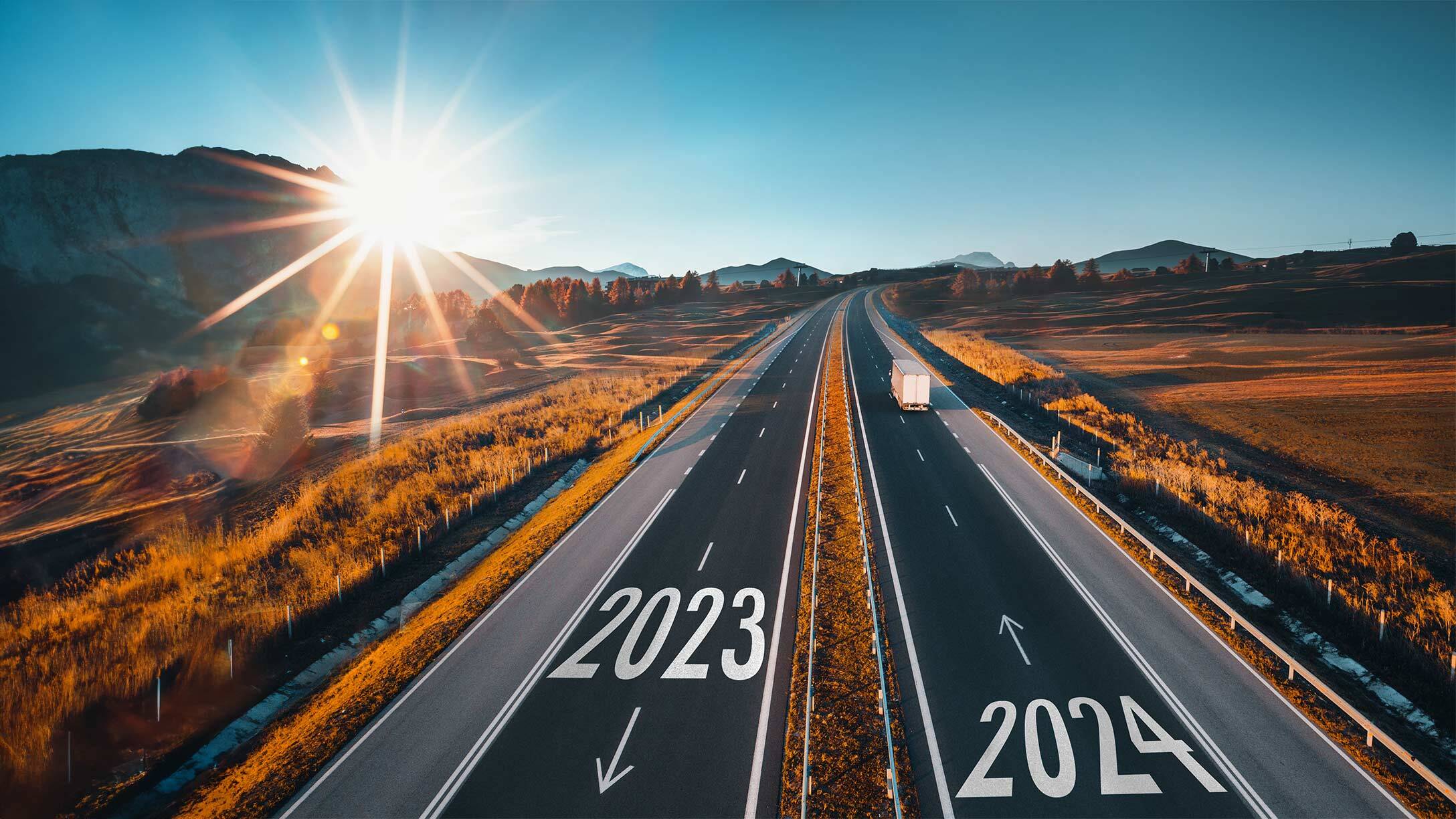 Road with 2024 painted on the asphalt and a truck driving down the road.