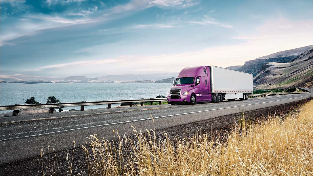 Purple Freightliner truck driving on a highway
