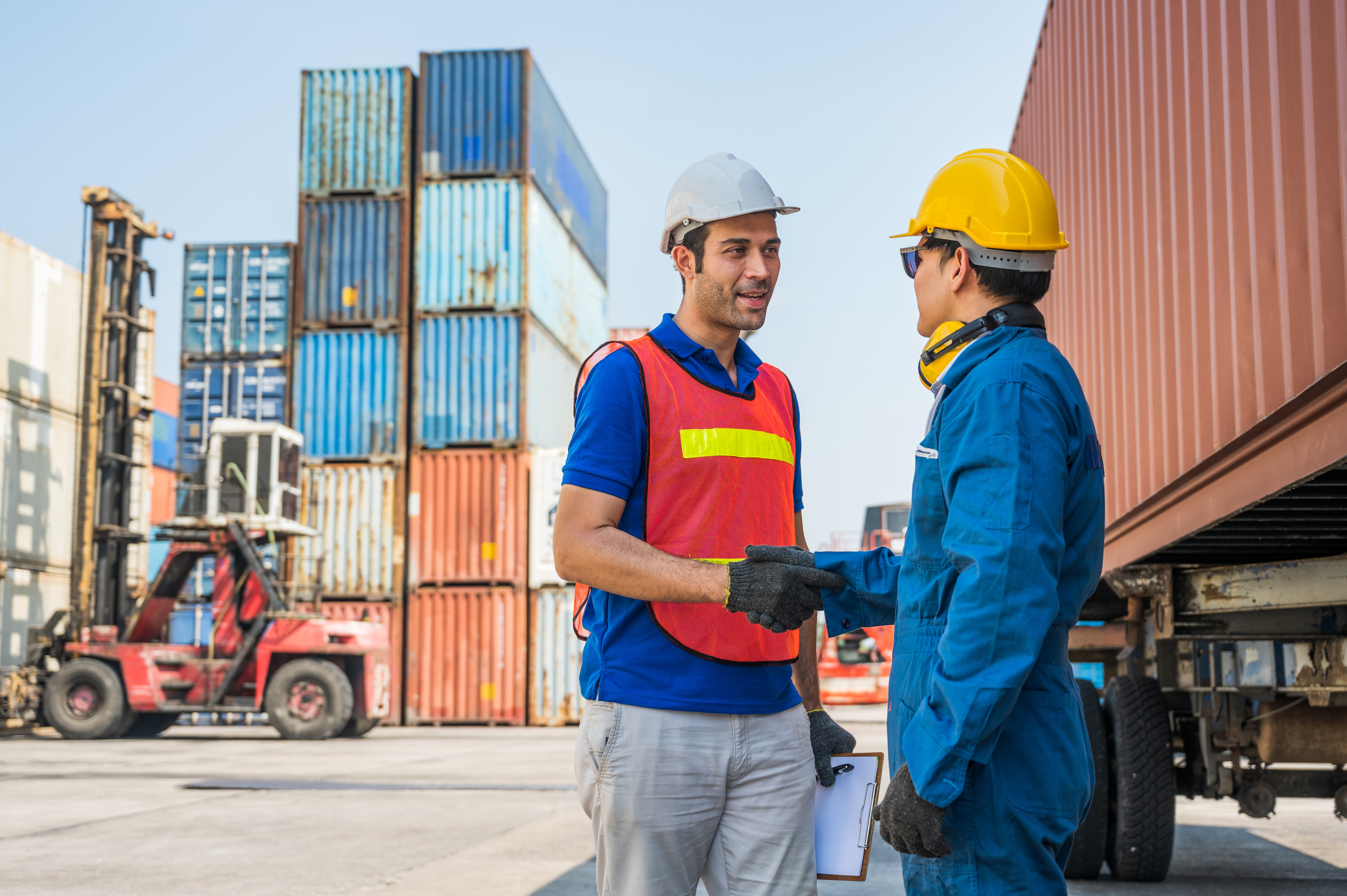 Workers shaking hands at a shipping yard