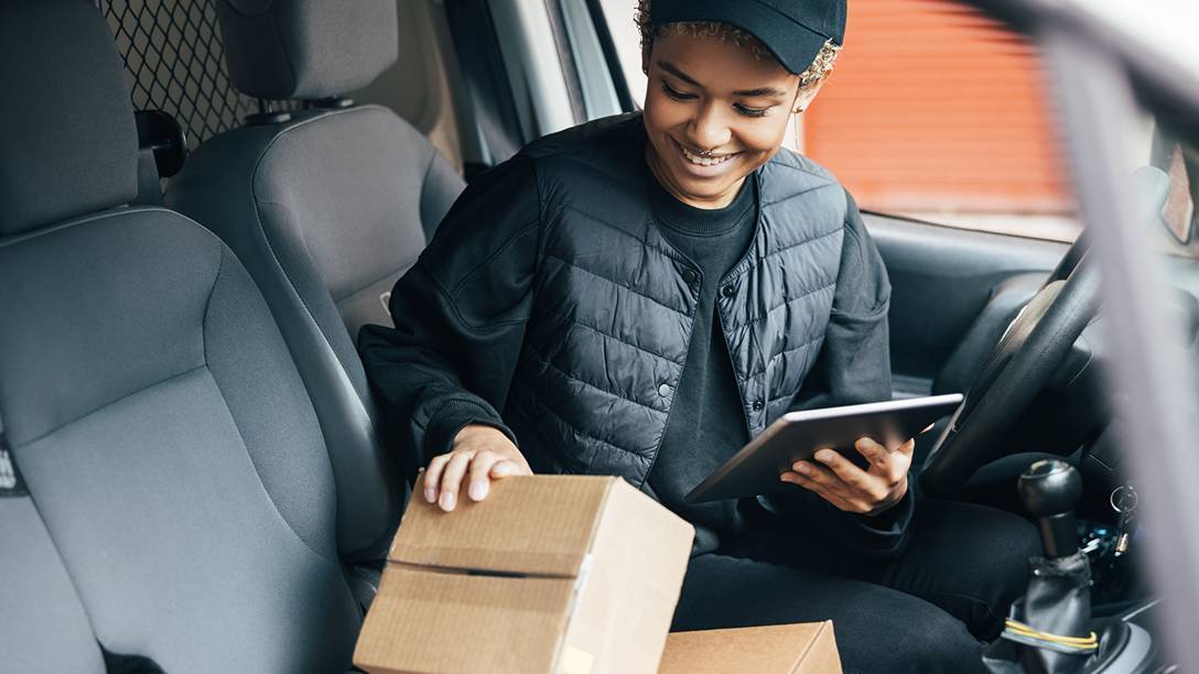 Courier in a van checking parcels with a tablet